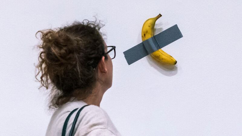 File - A woman looks at artist Maurizio Cattelan's piece of art "Comedian" during an auction...